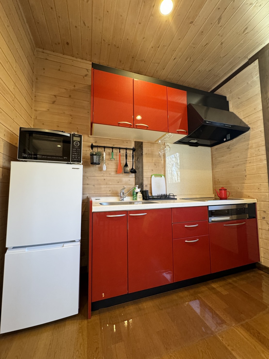 Second House ホッポッタ｜群馬県・北軽井沢・嬬恋・万座｜真っ赤なIHコンロ付きのシステムキッチンが、お部屋を明るく演出します。地元の高原野菜を使ったお料理にチャレンジするのも楽しそうですね。